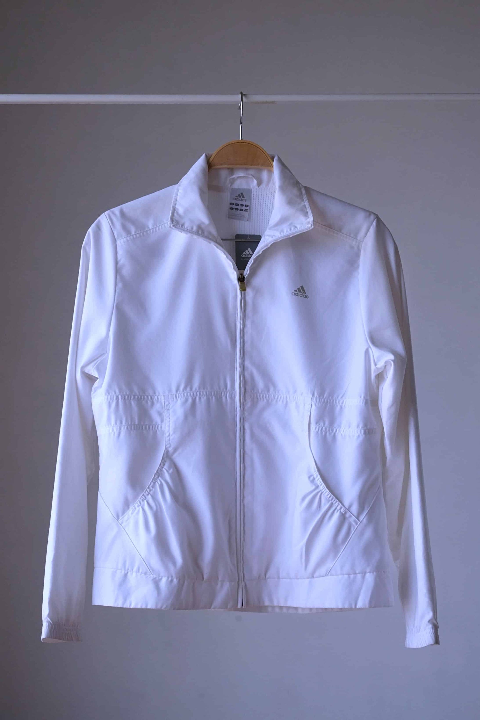 Vintage Adidas white windbreaker jacket with full-length zip, stand-up collar, and side pockets.