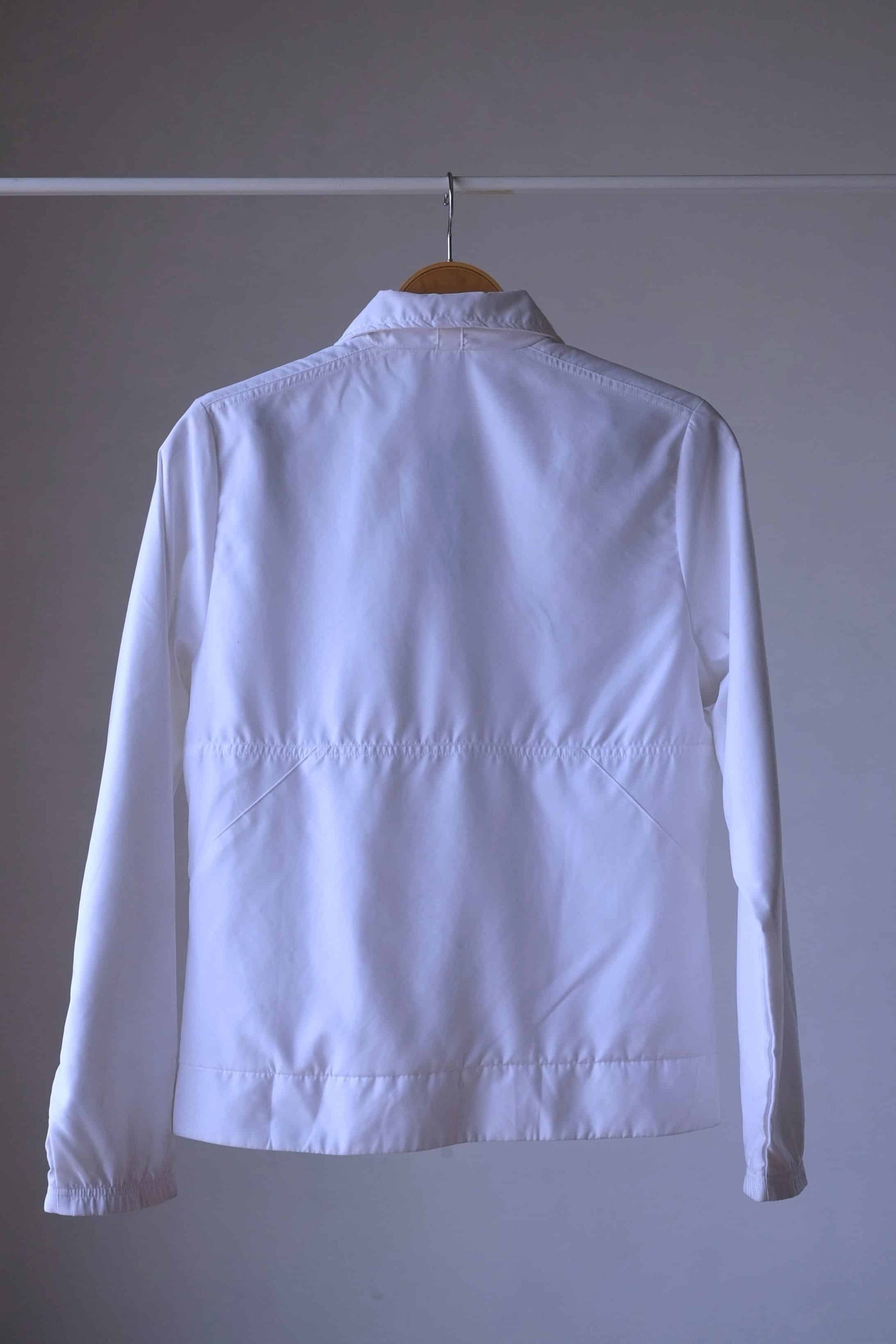 Backside of a Vintage Adidas white windbreaker jacket with full-length zip, stand-up collar, and side pockets.