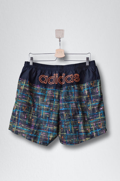 Back view shows a solid black top panel with a large orange ADIDAS logo and the abstract pattern below.