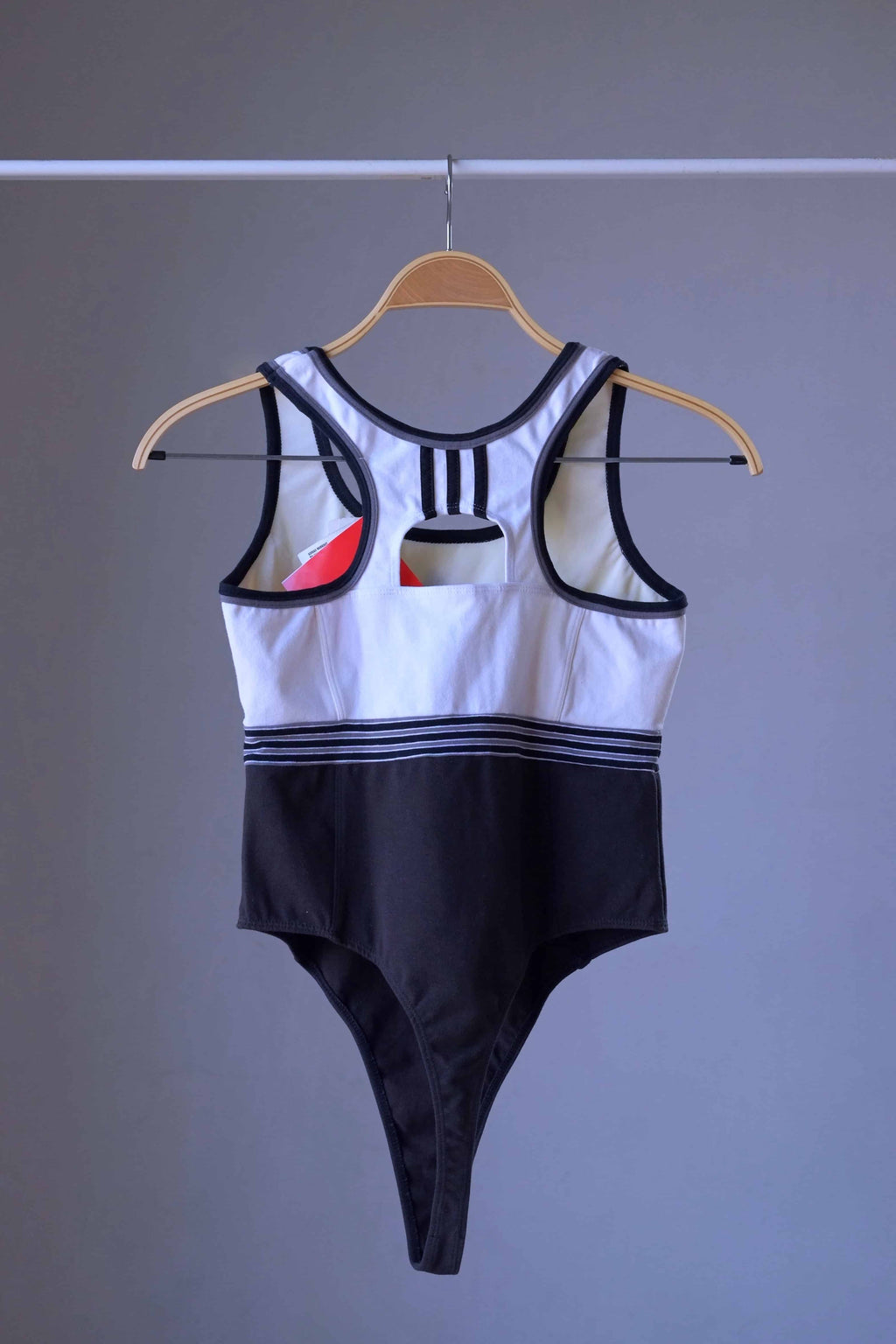 Back view of a vintage ADIDAS black and white thong-cut bodysuit with a racerback style.