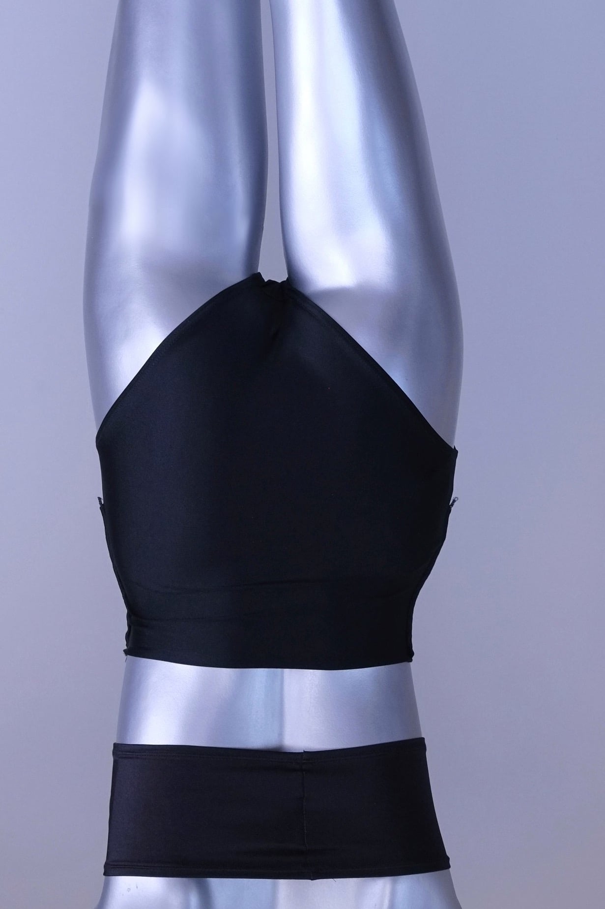 Back view of A pair of black, high-rise dance briefs with a folded-over waistband and a logo on the left hip, displayed on a mannequin.