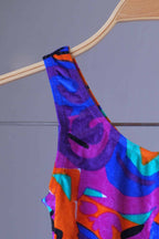 Close view of a colorful vintage Anniel one-piece leotard on a hanger.