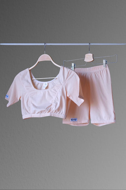 A nude color ANNIEL vintage 90s athletic crop top and shorts set displayed on hangers against a plain grey background. The set includes a cropped top with a wide neckline and matching fitted shorts.