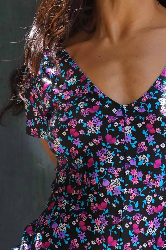 Close view of A person modeling an ANNIEL vintage 90s floral print activewear biketard with short sleeves and a V-neck, standing against a dark background.