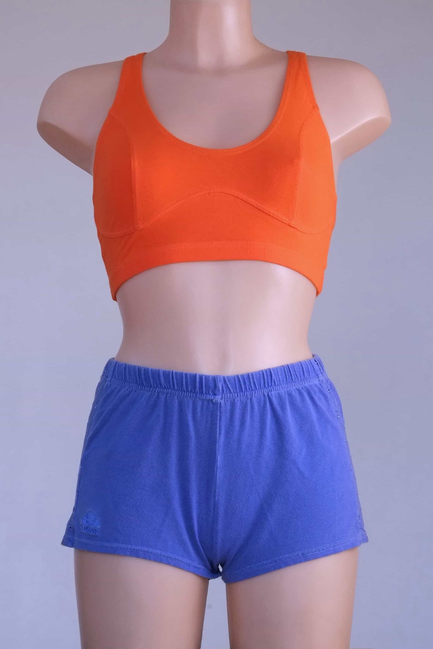 Front view of a mannequin wearing a Vintage 90s Anniel orange racerback sports bra and blue shorts, highlighting the keyhole detail.