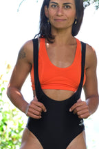 A woman wearing an orange sports bra with black detailing and a racerback design.