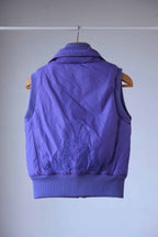 Back view of a purple Y2K-style puffer vest featuring intricate embroidered flame detailing with crystal embellishments. The ribbed hem and collar add a structured yet stylish touch.
