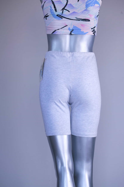 Back view of a mannequin wearing light ash gray vintage 90s BODY WRAPPERS bike shorts and a pastel print crop top.