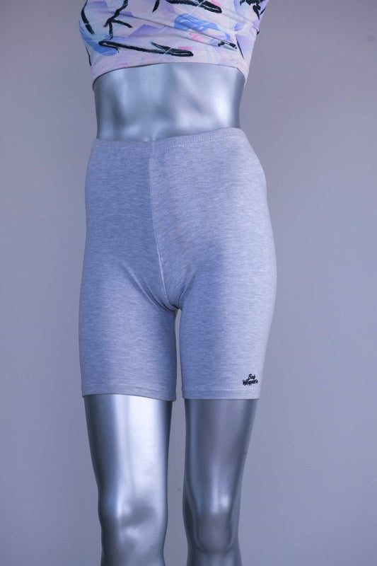 Front view of a mannequin wearing a slightly darker heather gray vintage 90s BODY WRAPPERS bike shorts and a pastel print crop top, with a small logo on the lower leg.