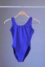 The vintage Body Wrappers leotard in purple, hanging on a clothes rack.