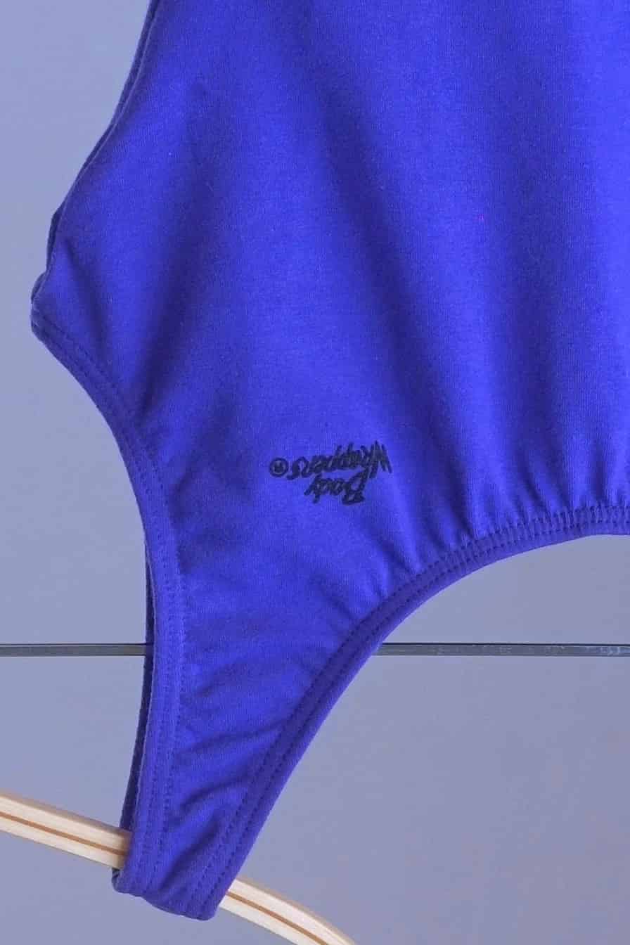 Close-up of the "Body Wrappers" logo printed on the front of the leotard.