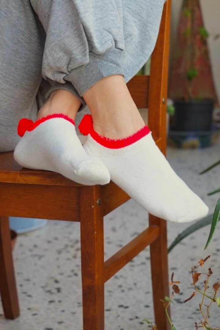 model's feet up on a chair and wearing red and white pom pom socks