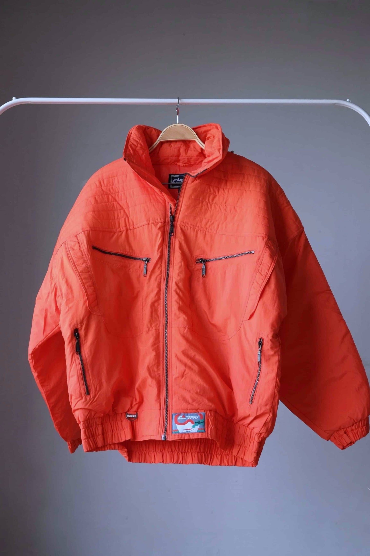 Vintage Campri ski jacket in neon orange. The jacket has an oversized puffer style with multiple pockets and an elasticated hem. 