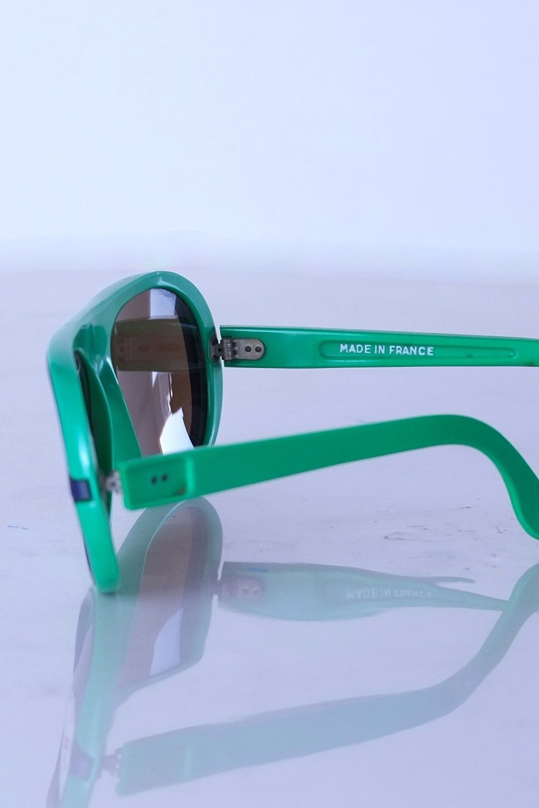 Close-up of the inner temple on green Cébé sunglasses featuring the white embossed "Made in France" manufacturing mark.