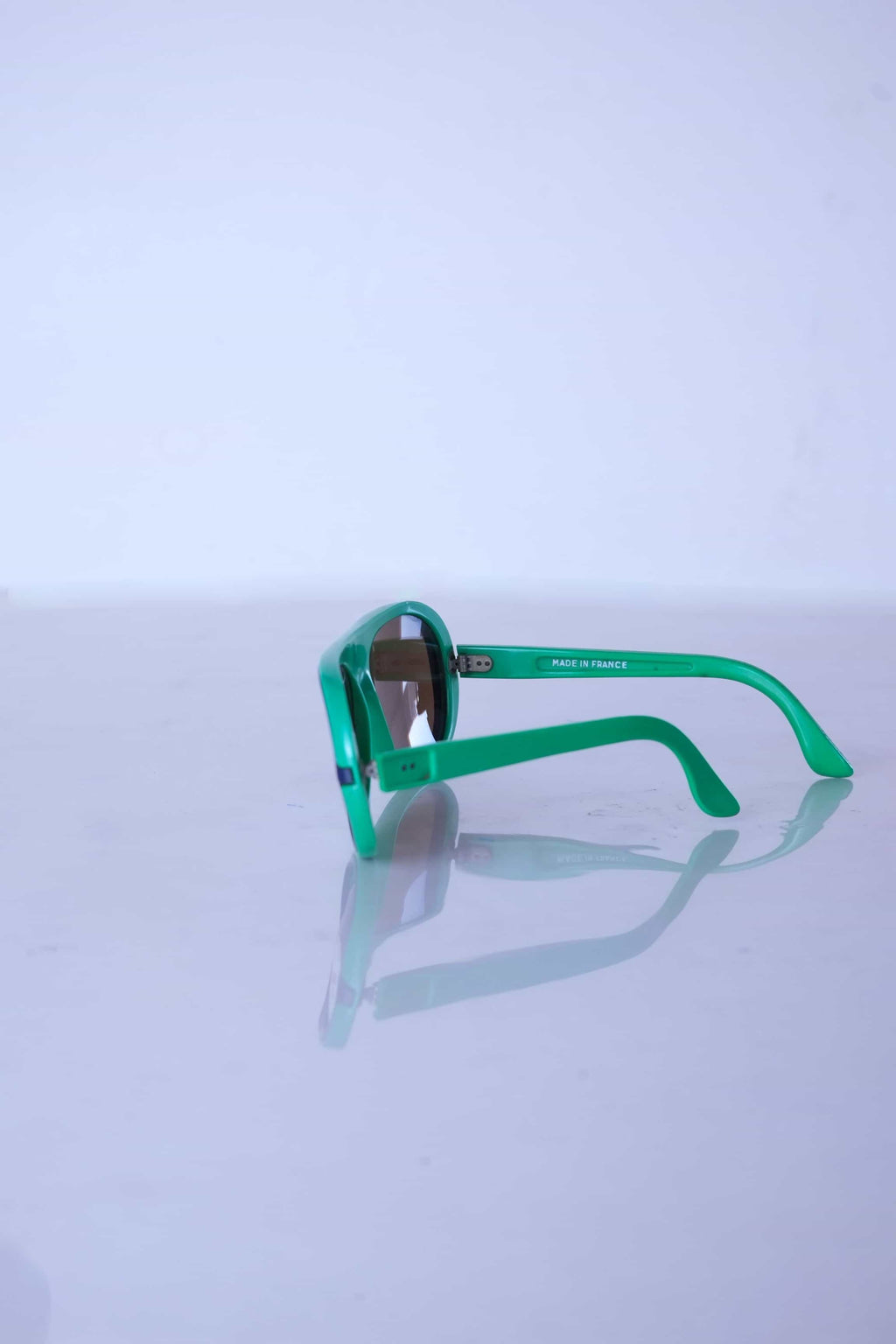 Side profile of green retro Cébé sunglasses showing the lightweight nylon frame construction and storage-related temple curve.