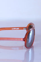 Tight Side view of translucent amber Cébé sunglasses highlighting the "CEBE" brand logo on the outer temple arm.