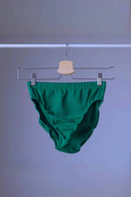 A pair of vintage Danskin high-cut dance briefs in emerald green, hanging on a clothes rack.