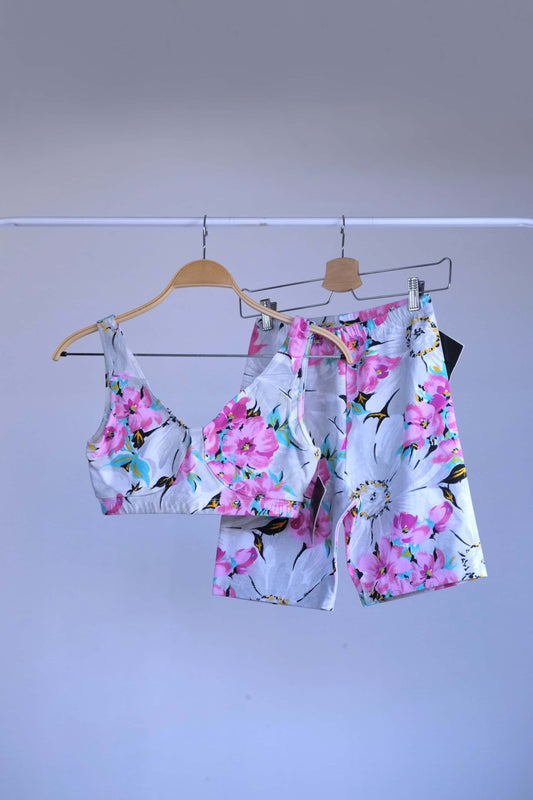A two-piece vintage 90s Danskin activewear set with a floral print, consisting of a bralette-style top and biker shorts, hanging on a metal rack.