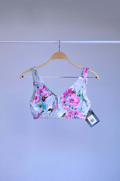 Front view of A vintage 90s Danskin activewear bralette-style crop top with a floral print, hanging on a metal rack.