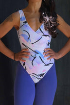 A model wearing the vintage Danskin leotard with a pastel abstract print, shown paired with blue leggings.