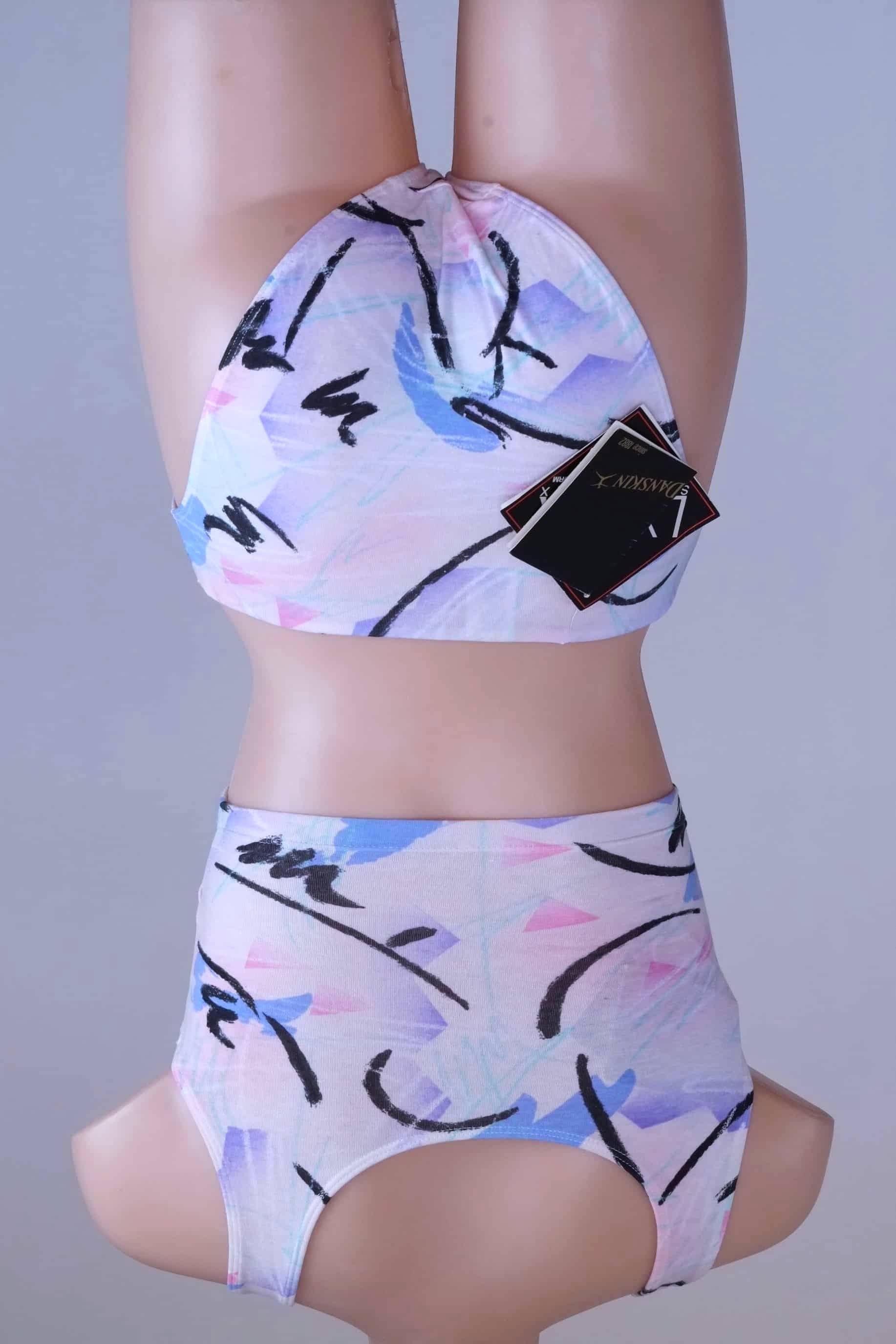 Back view of a DANSKIN vintage 90s matching activewear set, featuring a pastel abstract print crop top and high-cut briefs, displayed on a mannequin.