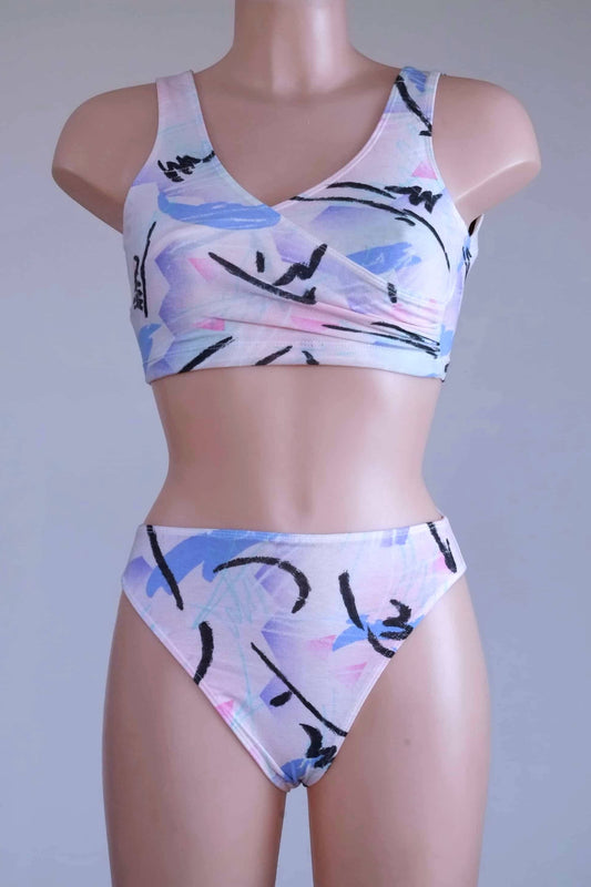 A DANSKIN vintage 90s matching activewear set, featuring a pastel abstract print crop top and high-cut briefs, displayed on a mannequin.