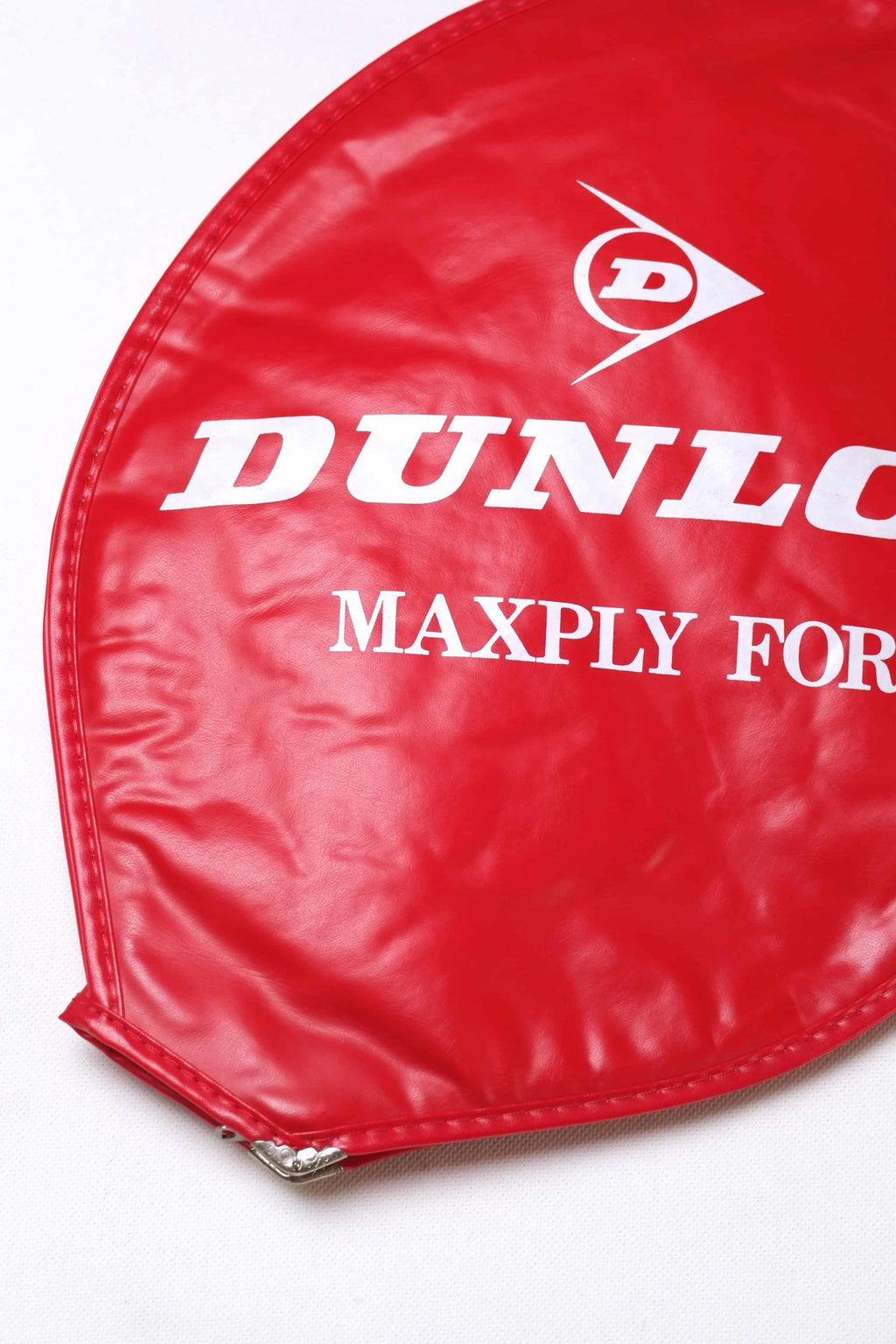 Close-up shot of the white printed Dunlop Maxply Fort logo on a vibrant red textured vinyl vintage tennis racket cover.