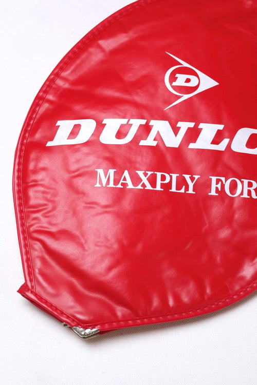 Close-up shot of the white printed Dunlop Maxply Fort logo on a vibrant red textured vinyl vintage tennis racket cover.