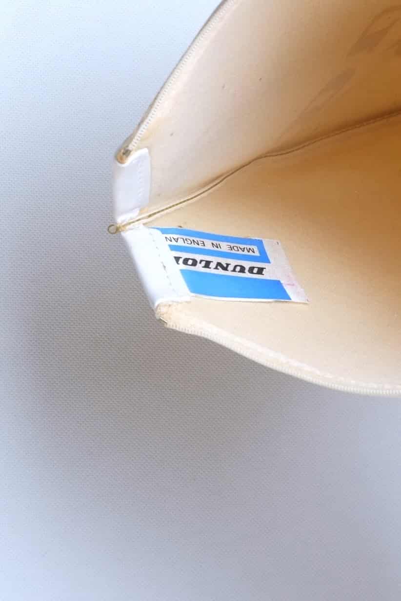 Interior detail of a vintage white vinyl Dunlop tennis racket cover showing the original blue and white "DUNLOP Made in England" cloth tag.