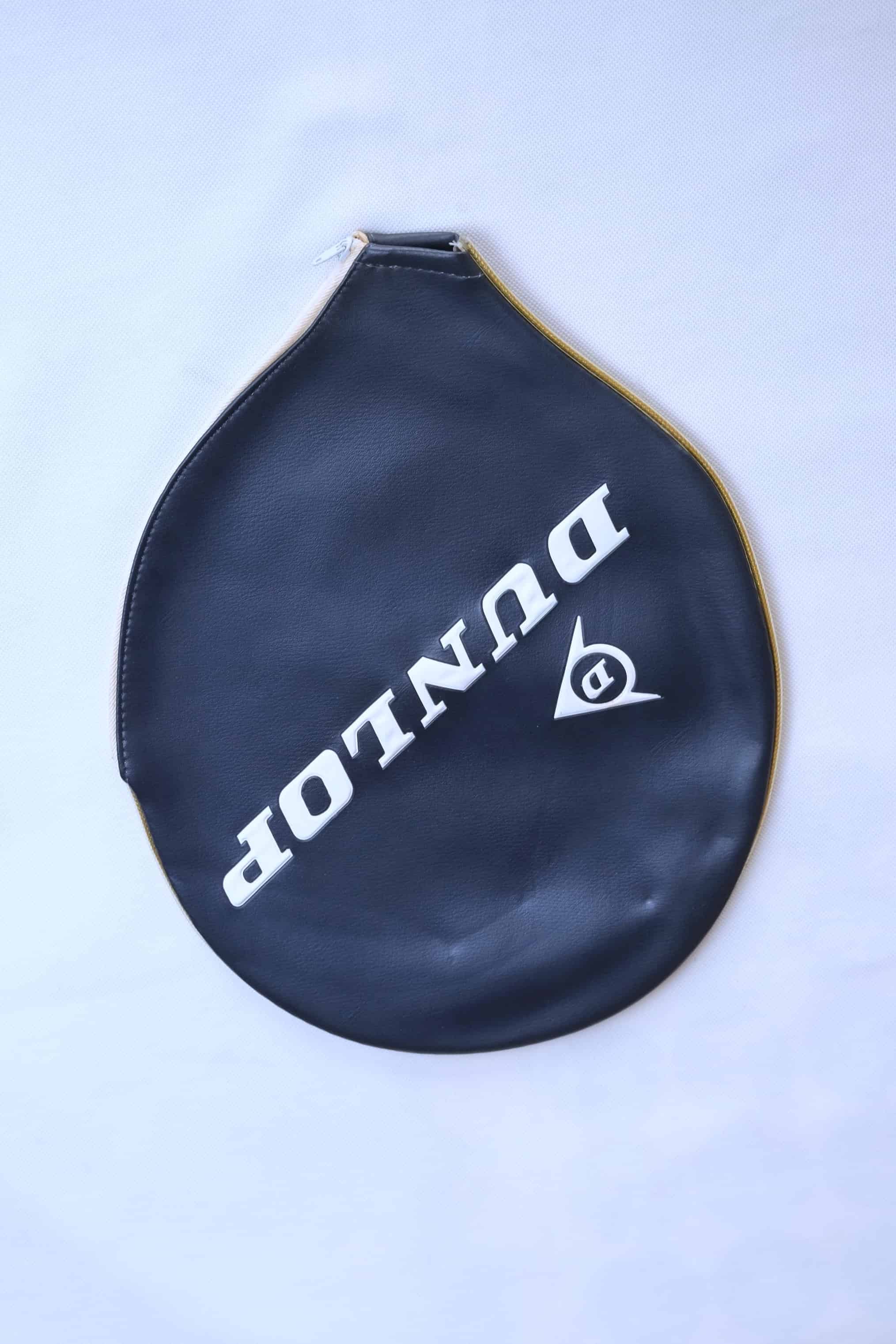 Vintage navy vinyl Dunlop tennis racket zippered head cover with diagonal white branding, shown on a clean white backdrop.
