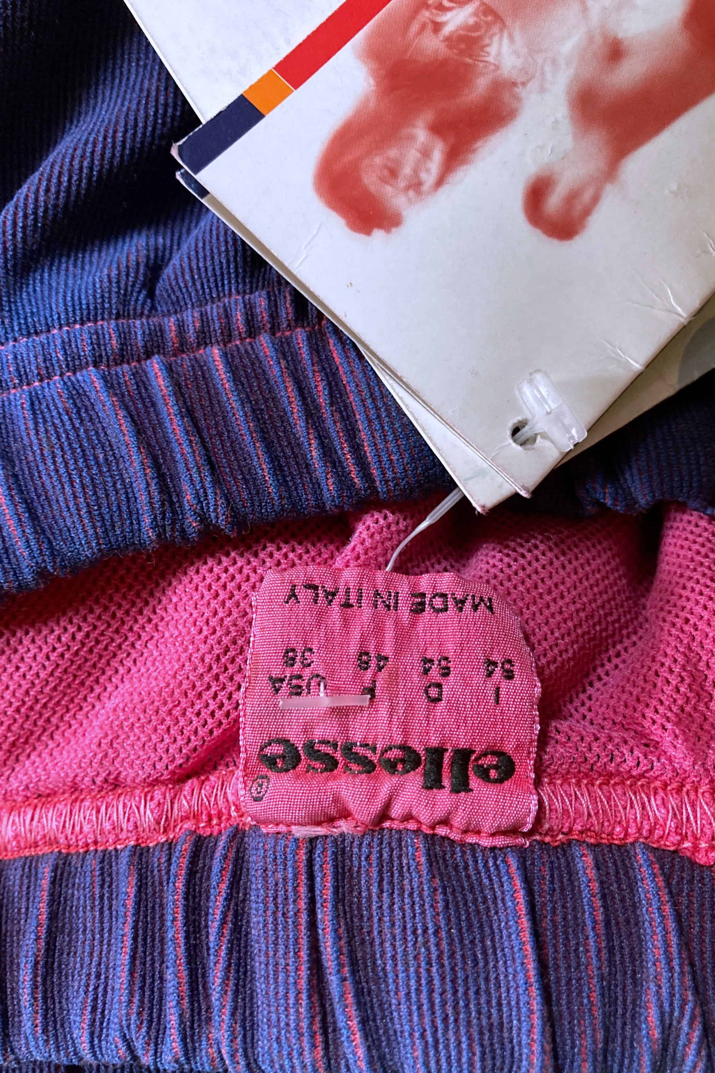 Close-up of pink Ellesse size tag reading 54 Italy, 38 USA, made in Italy.