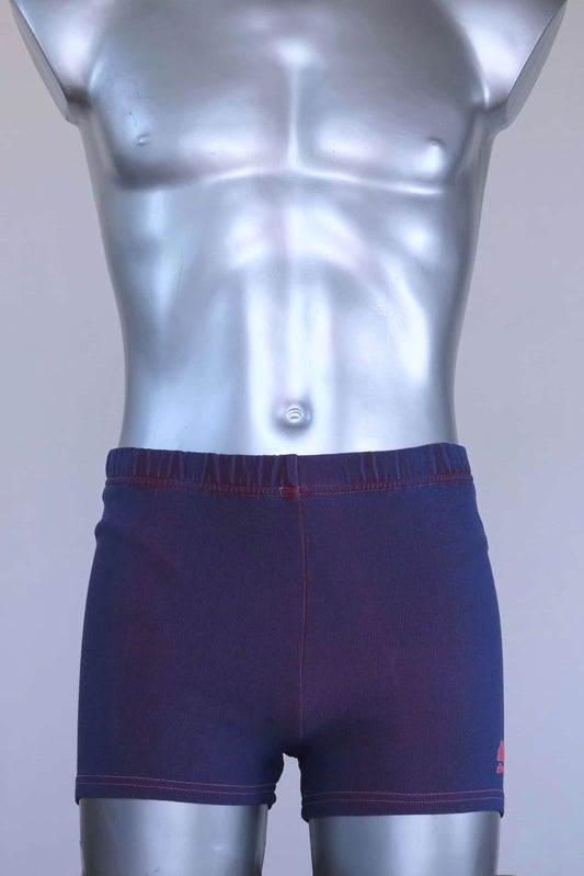 Vintage 90s Ellesse men’s swim trunks in deep purple ribbed stretch knit with pink contrast stitching, shown on a silver mannequin.