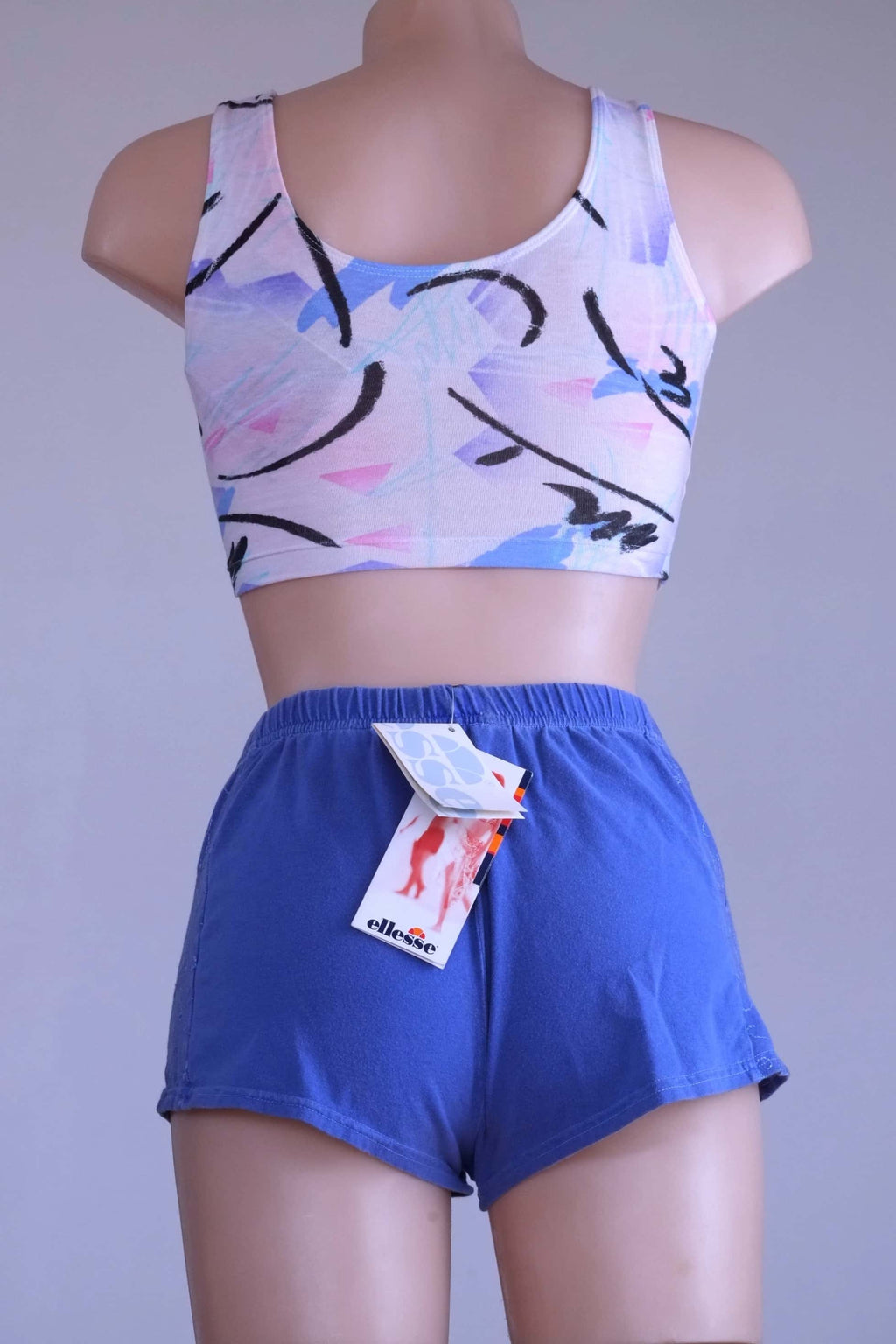 Back view of mannequin wearing vintage Ellesse embroidered terry hot pants in blue, with the tags showing.