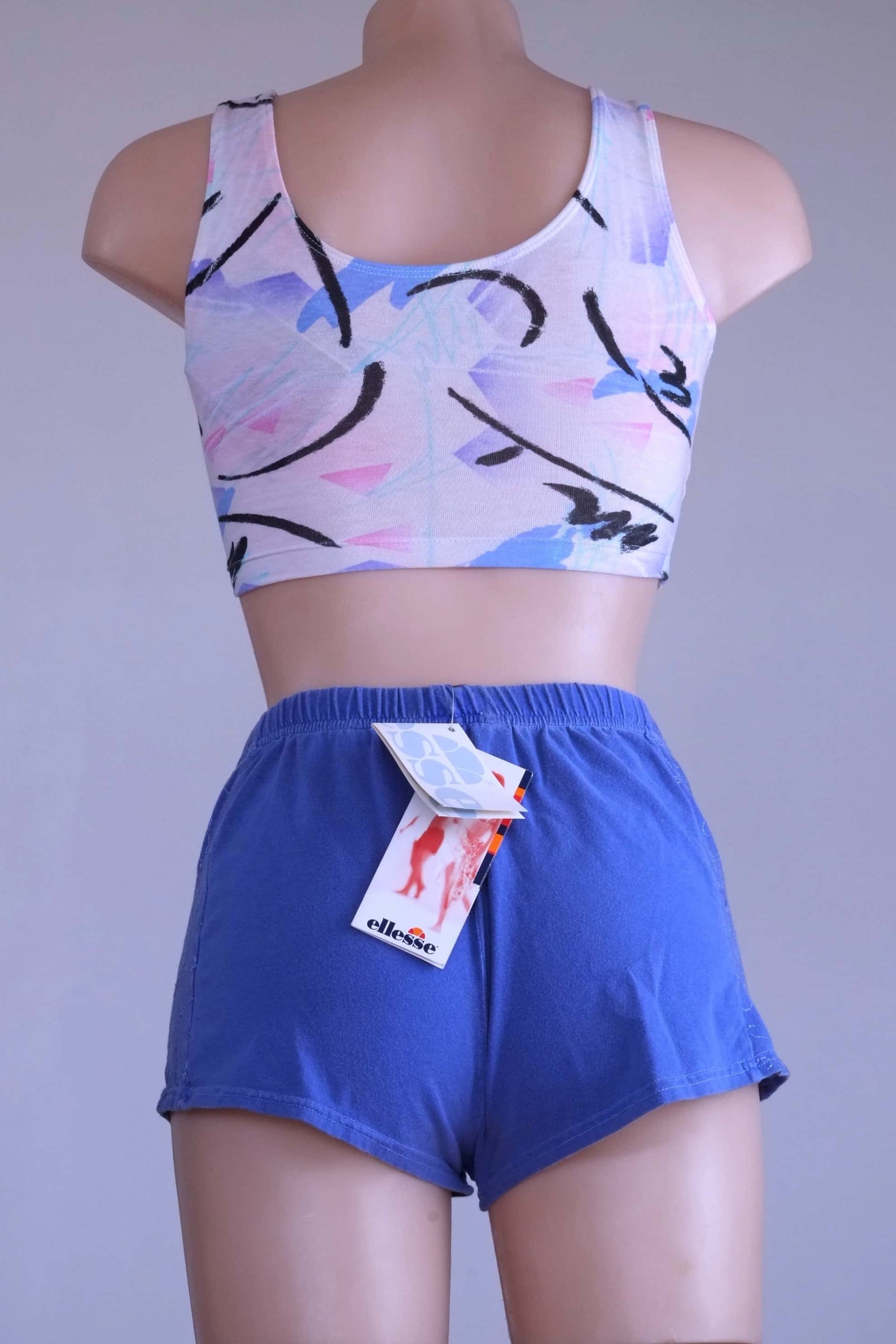 Back view of mannequin wearing vintage Ellesse embroidered terry hot pants in blue, with the tags showing.