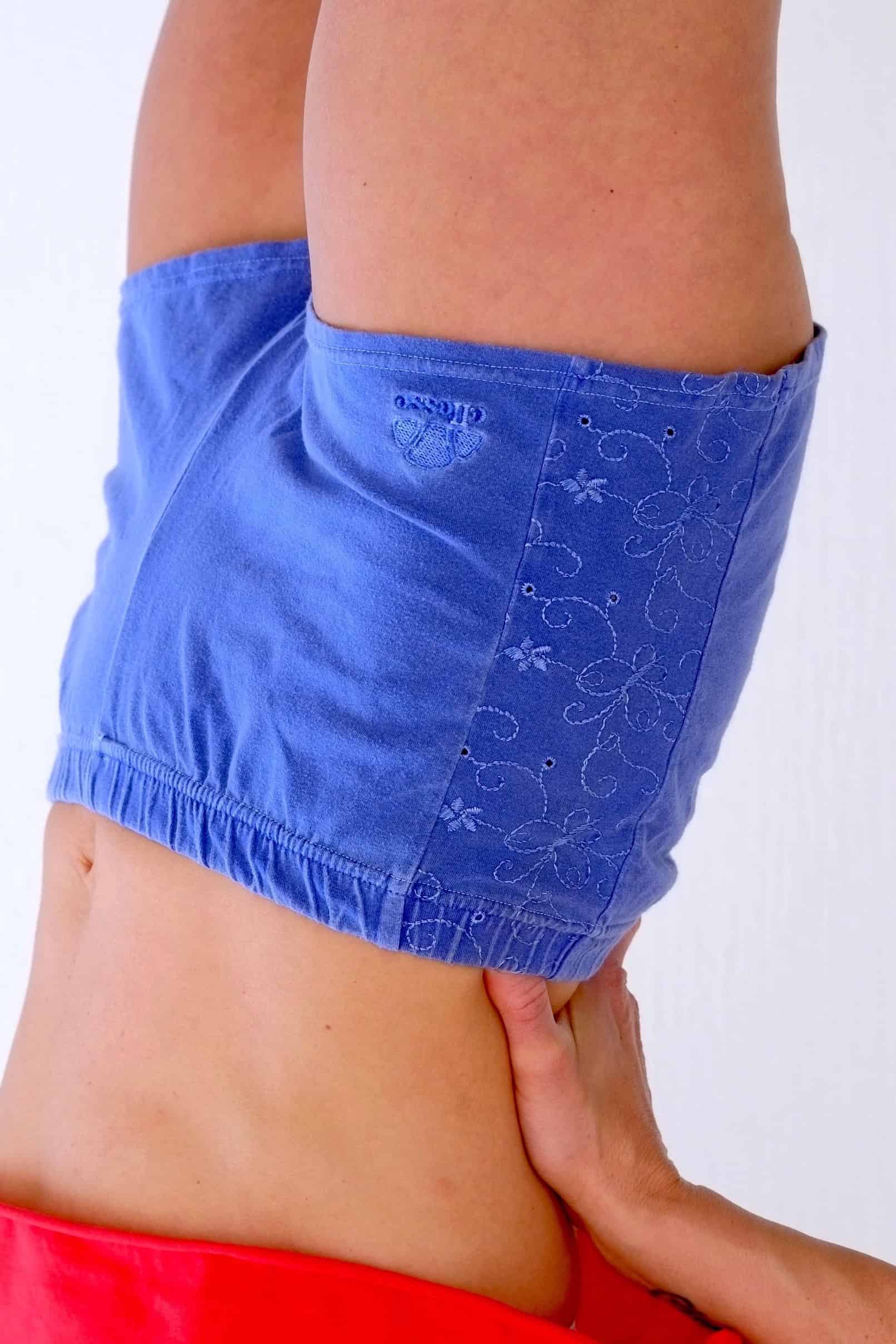 Close-up of vintage Ellesse blue terry hot pants with floral embroidery and logo.