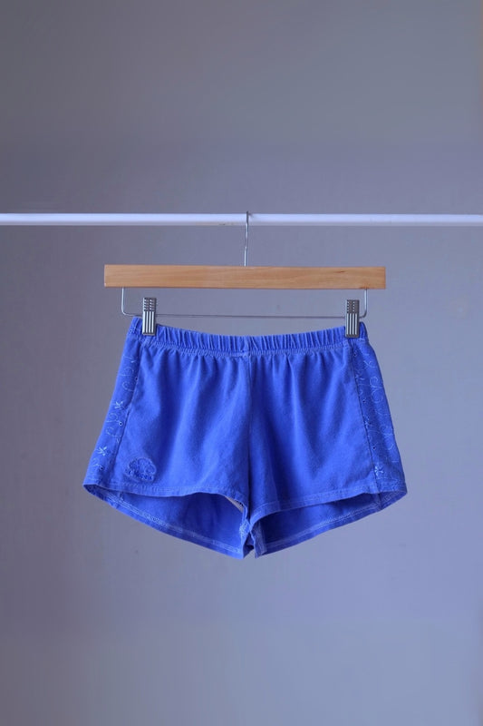 Vintage Ellesse embroidered terry cloth hot pants in blue, displayed on a hanger.