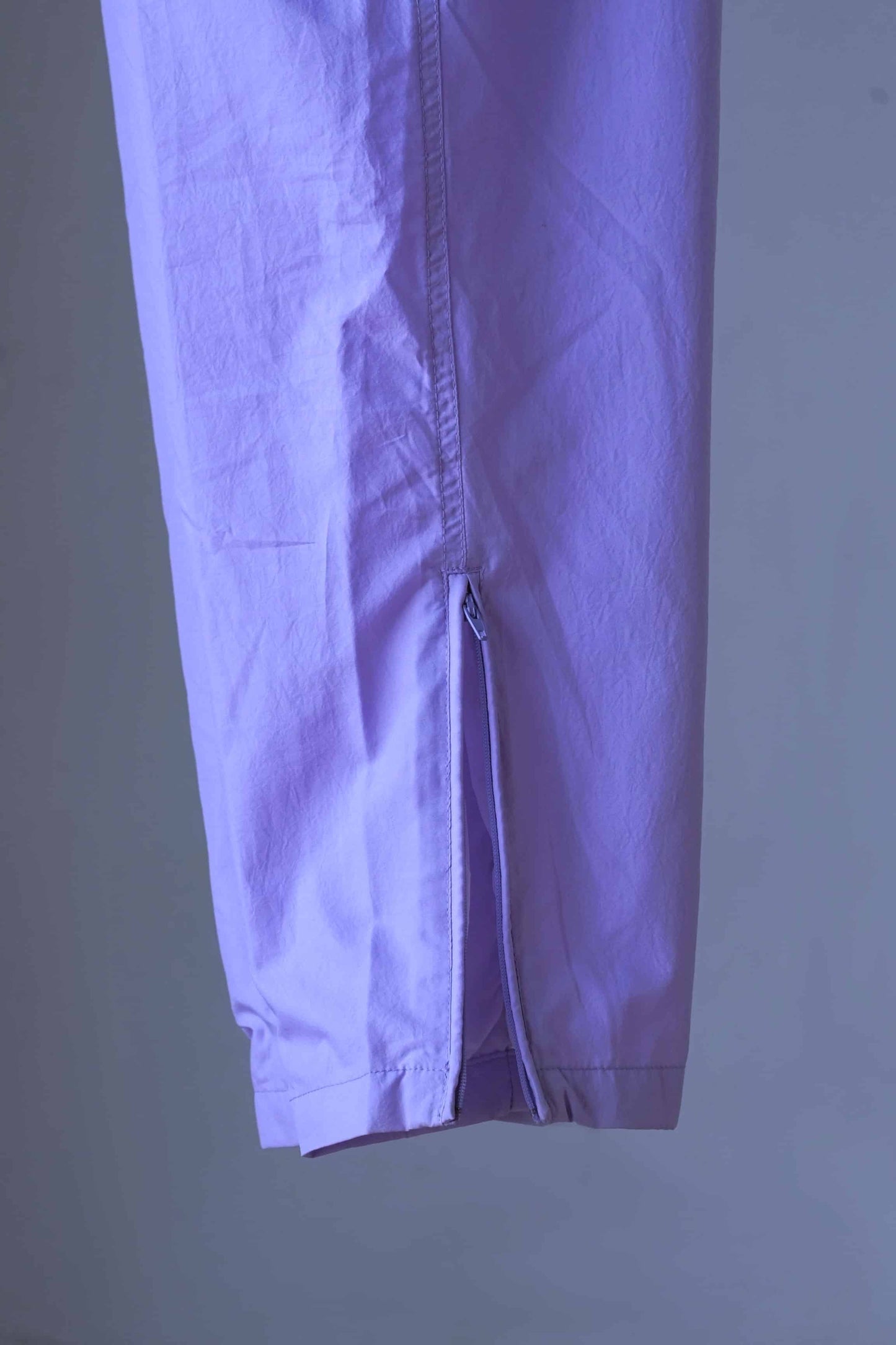 Detail of ankle zippers on a pair of Vintage Ellesse pants in a lilac shade.