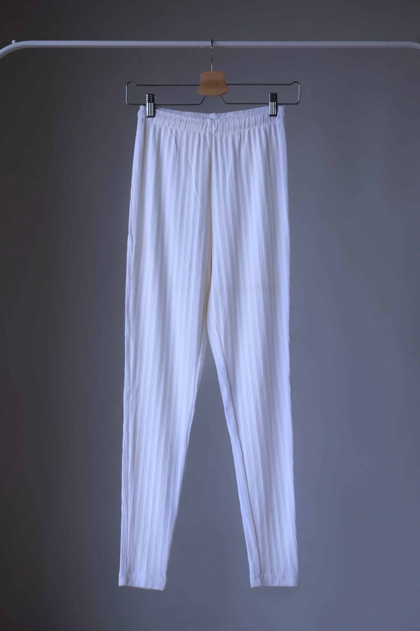 High-waisted, ribbed white leggings hanging on hanger.