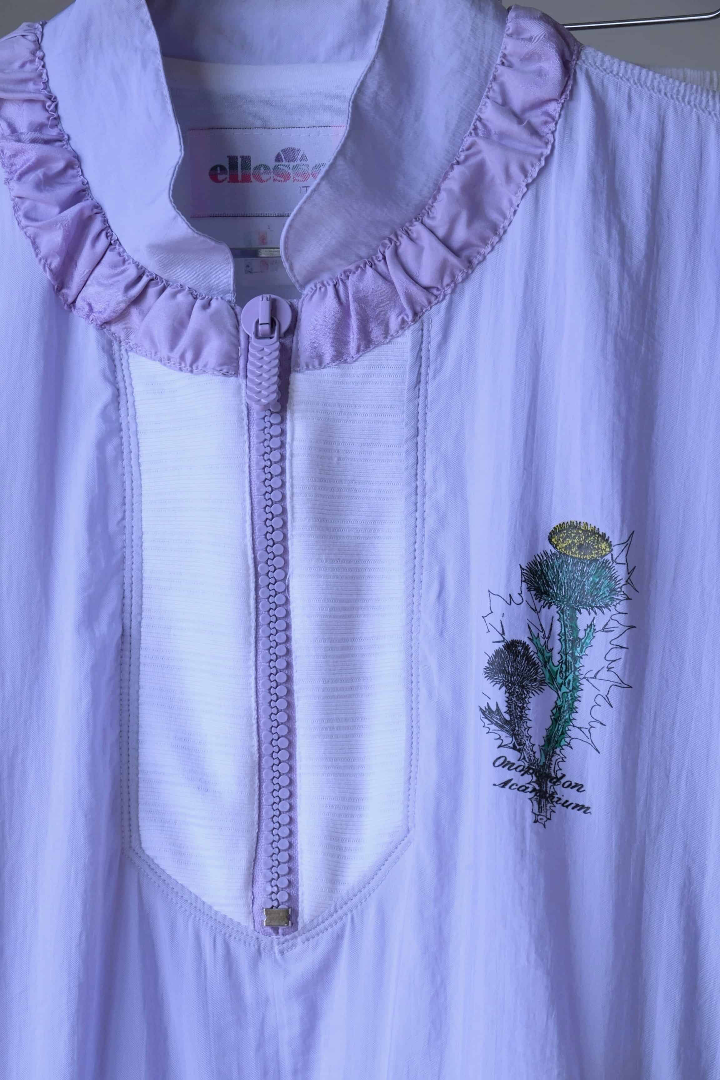 Detail of the Ellesse brand logo and floral print on a pastel purple Vintage Ellesse jacket.