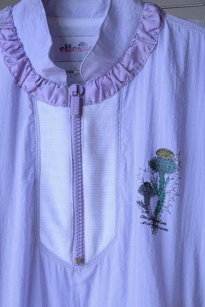Detail of the Ellesse brand logo and floral print on a pastel purple Vintage Ellesse jacket.
