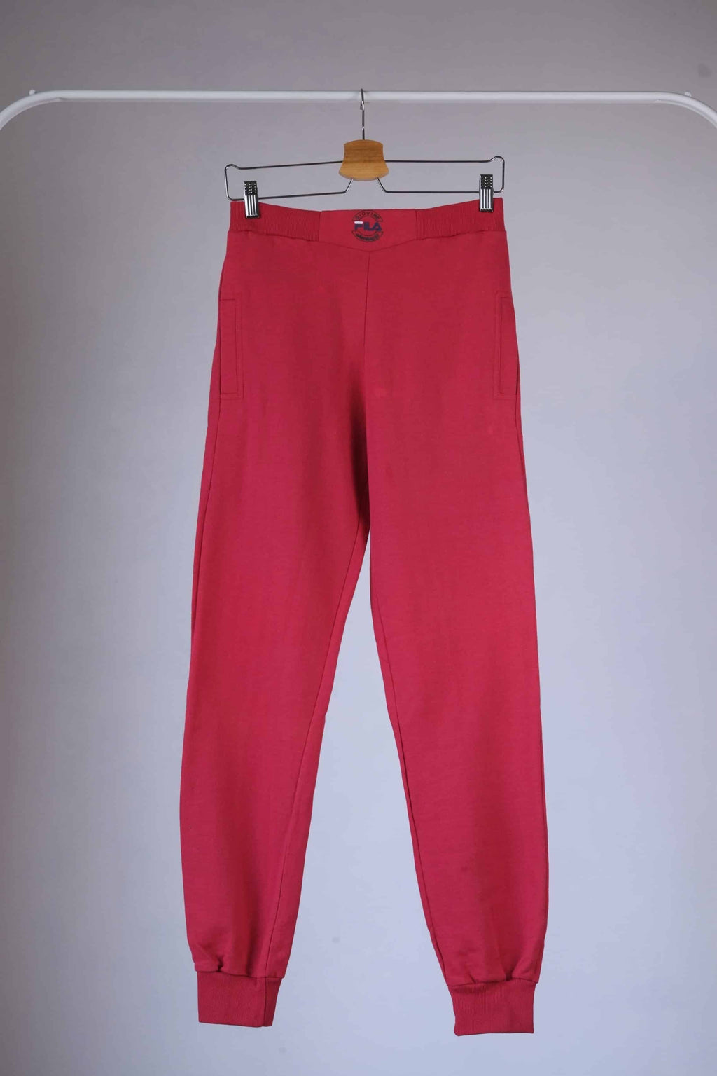 Red Fila 90s vintage jogging pants hanging on a hanger.