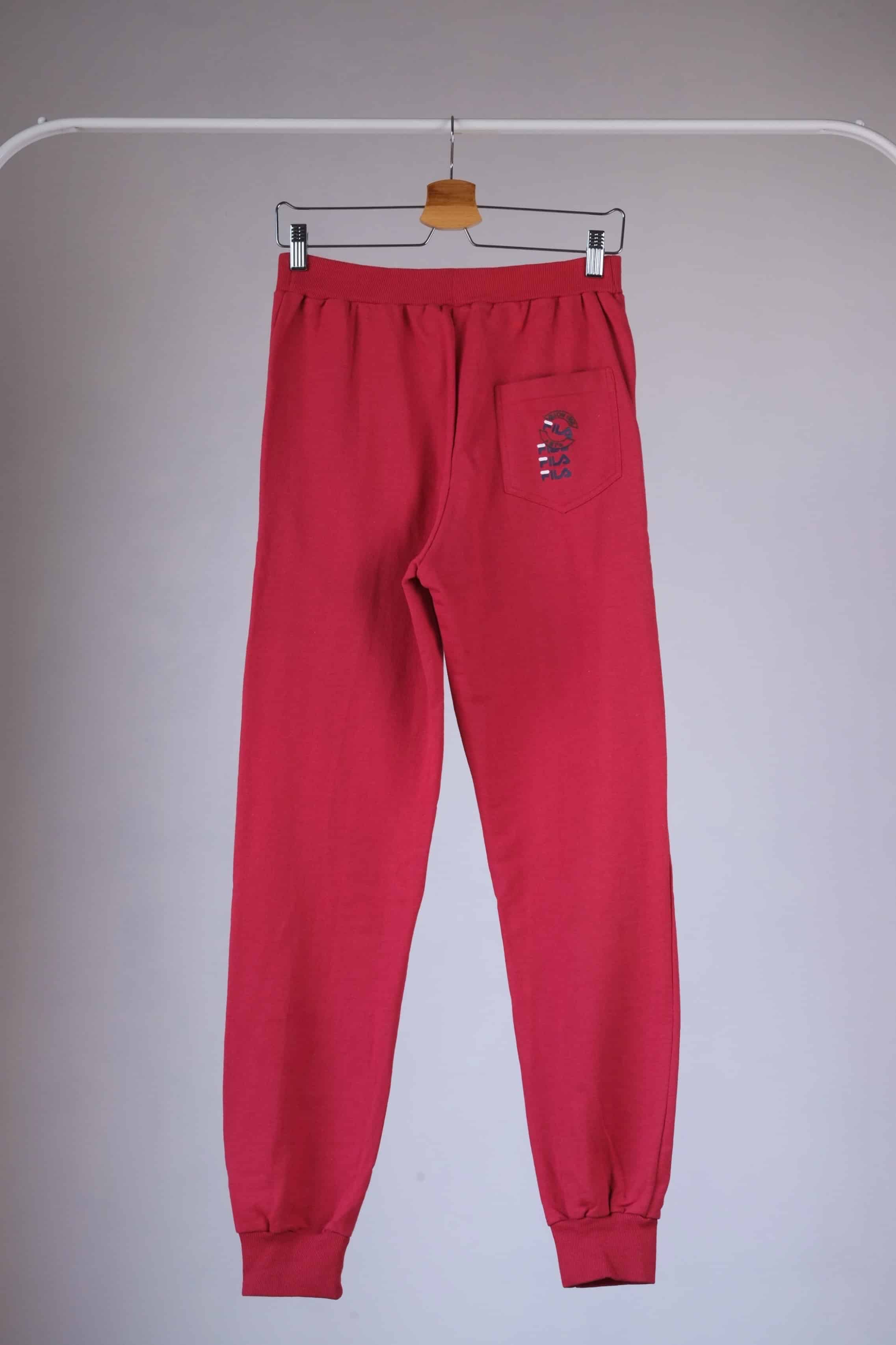 Back view of red Fila 90s vintage jogging pants hanging on a hanger.