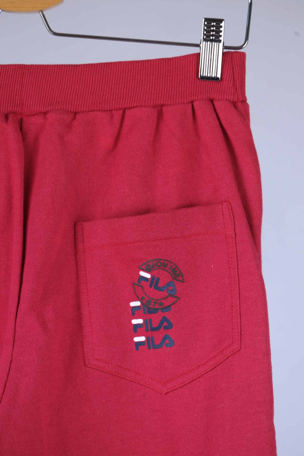 Close-up of the back pocket of red Fila 90s vintage jogging pants, showing the Fila logo in black, red, and blue.