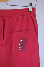 Close-up of the back pocket of red Fila 90s vintage jogging pants, showing the Fila logo in black, red, and blue.
