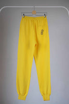 Back view of Yellow Fila 90s vintage jogging pants hanging on a hanger.