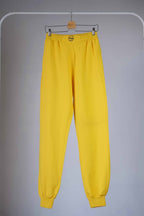 Yellow Fila 90s vintage jogging pants hanging on a hanger.