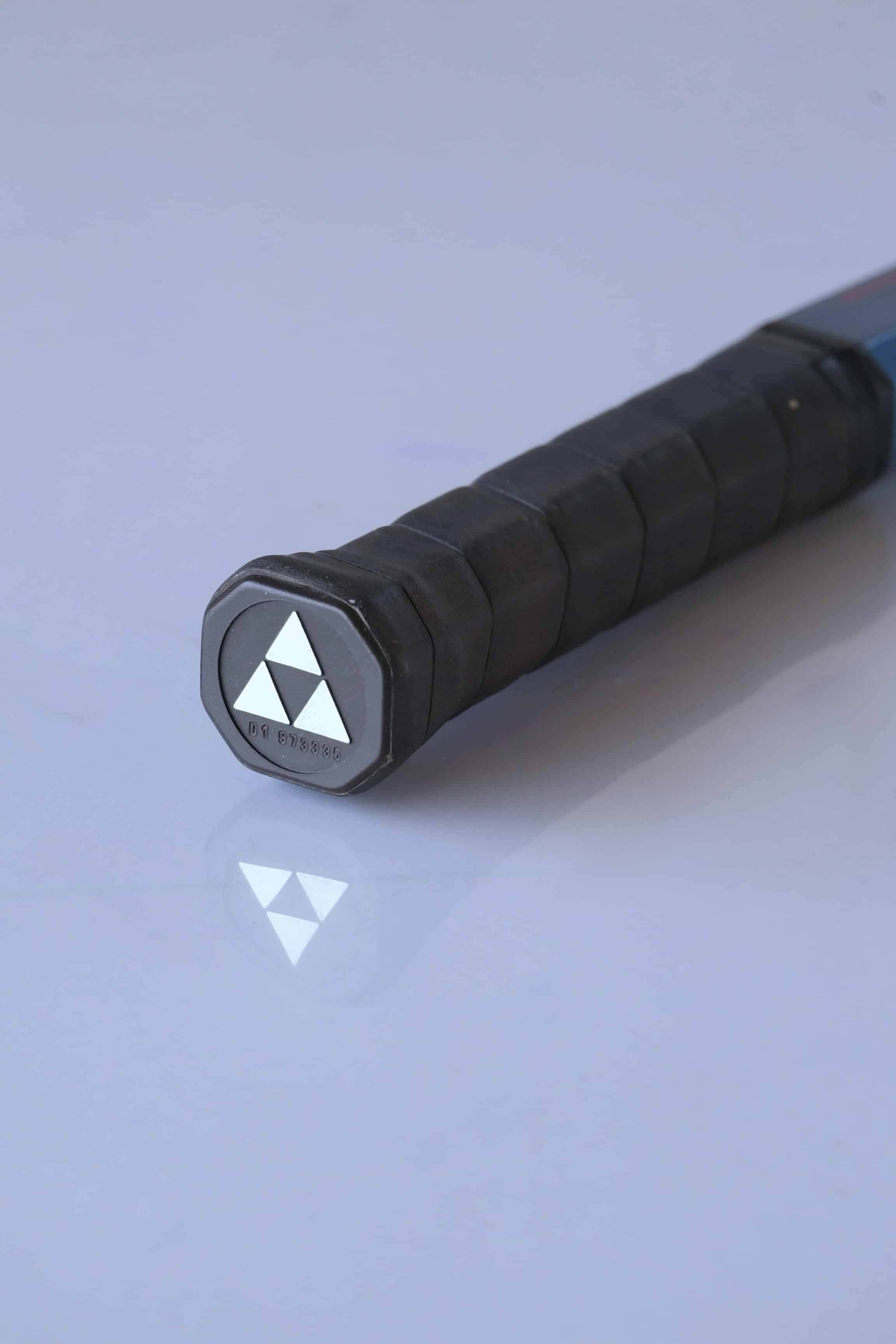 Close-up of a tennis racket handle with a black grip.
The cap handle features the Fischer logo that is made up of three triangles.