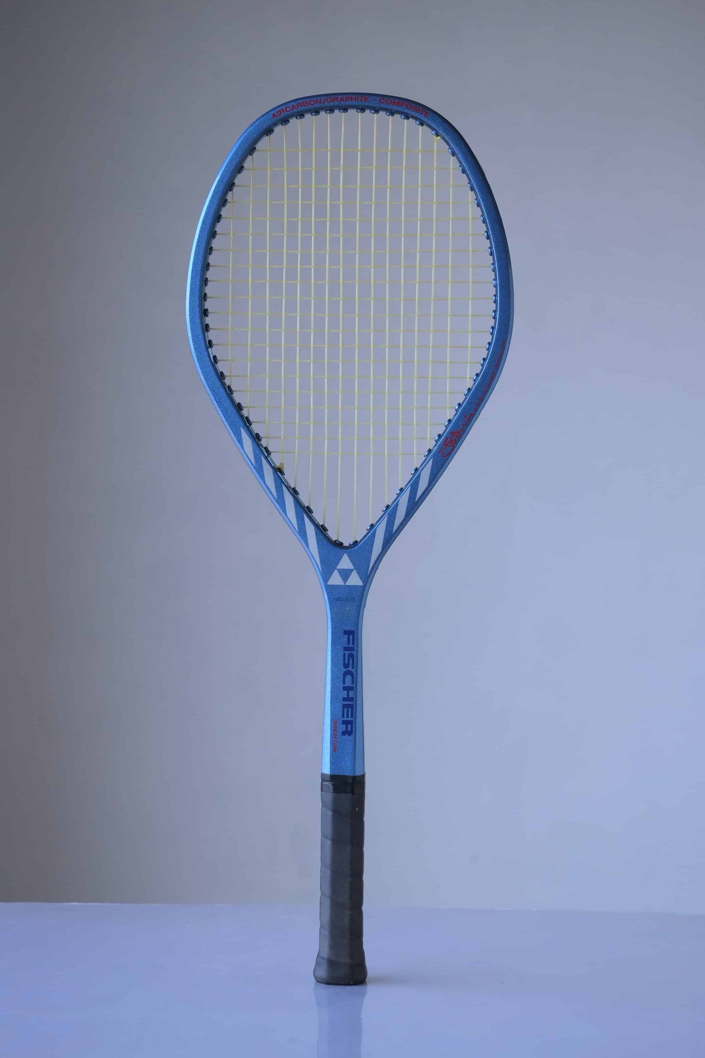 Vintage Fischer Superform Jo Durie tennis racket. The racket has a blue frame with white accents and a black handle. The strings are yellow. The word "FISCHER" is written in white on the frame.