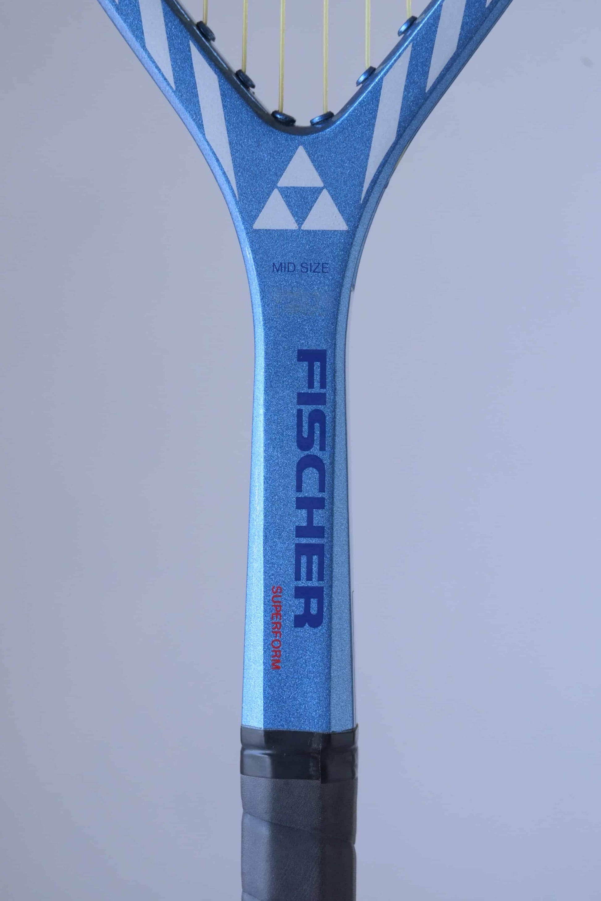 Close-up of a tennis racket neck with a blue and black handle.
 The word "FISCHER" is written in navy on the handle, with "SUPERFORM" written below it. The words "MID SIZE" are also visible on the handle, as well as the triangular Fischer logo. The racket frame has a diamond-shaped pattern with blue and white stripes.