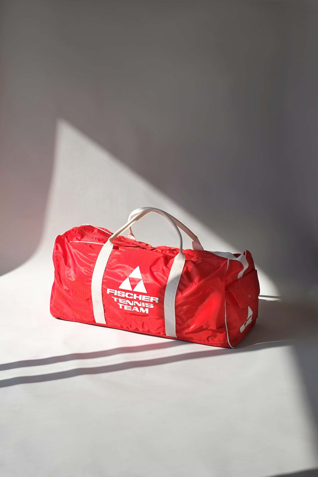 Full view of a vintage red Fischer Tennis Team sports duffle bag featuring white logo and bold text.